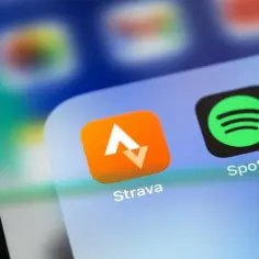 Ikona aplikacji Strava, idealnej do śledzenia tras rowerowych, obok Spotify na ekranie smartfona.