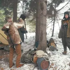 Oto przykład, bushcraft co to: ludzie w zimowym lesie, namiot, sprzęt i futrzane okrycie.