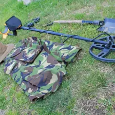 Wykrywacz metali, łopata, mundur i kapelusz na trawie.