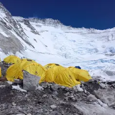 Obóz na wyprawę na Mount Everest. Żółte namioty na kamienistym podłożu, w tle lodowiec i ośnieżone szczyty.