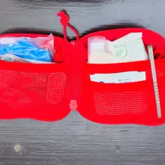 Czerwona saszetka edc z plastrami, rękawiczkami i pęsetą, gotowa na każdą sytuację.