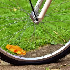 Płaska dętka rowerowa leży na trawie, obok pomarańczowego odblasku.