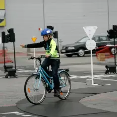 Chłopiec w kasku uczy się przepisów ruchu drogowego na rowerze. Karta rowerowa od ilu lat? Od 10.