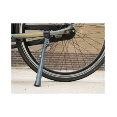 Szara stopka rowerowa podtrzymuje rower, opierając się o betonową nawierzchnię.