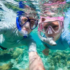 Para dwojga podczas snorkelingu, podziwiająca podwodny świat i rafy koralowe.