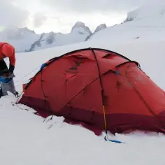 Wspinacz przygotowuje namiot na śniegu. Zastanawiasz się, ile kosztuje wejście na Mount Everest? To przygoda życia!