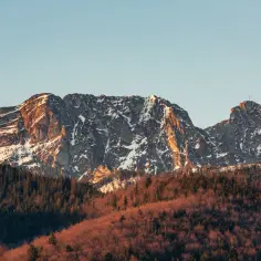 Giewont oświetlony słońcem, z lasem u podnóża. Zastanawiasz się, ile się wchodzi na Giewont? To zależy od kondycji i pogody!