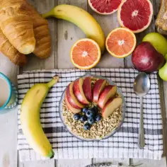 Pyszne i zdrowe śniadanie: owsianka z jabłkiem i jagodami, banan, cytrusy, croissanty i kawa.