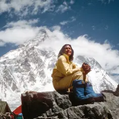 Junko Tabei, pierwsza kobieta, która zdobyła Mount Everest, siedzi na skale, podziwiając majestatyczne szczyty.
