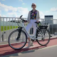 Kobieta z rowerem elektrycznym na ścieżce. Czy na rower elektryczny trzeba mieć prawo jazdy? Zależy od mocy silnika.