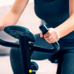 Kobieta ćwiczy na rowerze stacjonarnym, szukając odpowiedzi, jaki rower stacjonarny na odchudzanie będzie najlepszy.