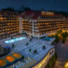 Hotel Gołębiewski Wisła nocą, z oświetlonymi basenami i tarasami pełnymi leżaków, pod rozgwieżdżonym niebem.