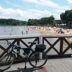 Rower na pomoście nad pełnym ludzi jeziorem Przeczyckim. Słońce, plaża i kąpielisko tętnią życiem.
