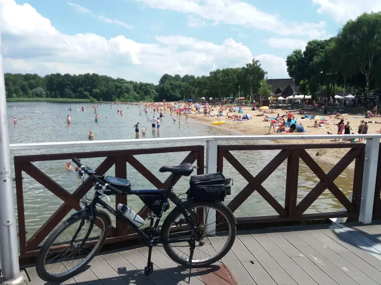 Rower na pomoście przy pogoria jezioro. Tłumy ludzi kąpią się i opalają na plaży w słoneczny dzień.