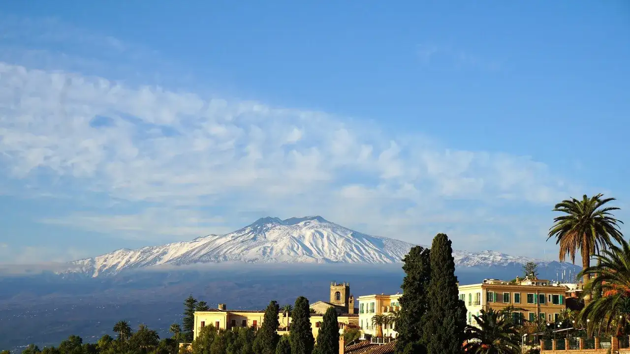 Ośnieżony Etna góruje nad miasteczkiem na największej wyspie na Morzu Śródziemnym.