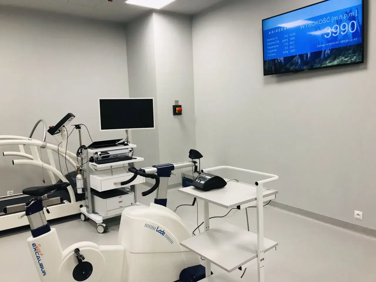 Nowoczesna komora hipoksyjna z bieżnią, rowerem stacjonarnym i monitorem parametrów.