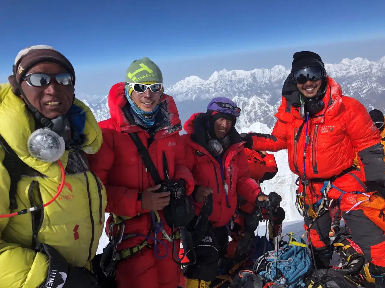 Czterech wspinaczy w zimowych ubraniach na szczycie góry, z widokiem na ośnieżone szczyty. Czy to oni są tymi, którzy jako pierwsi zdobyli Mount Everest?