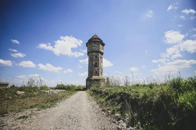 Stara wieża ciśnień w Szopienicach, zniszczona, ale wciąż majestatyczna, stoi na tle błękitnego nieba z chmurami.